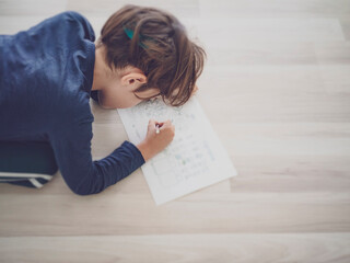 young boy doing his homework on the floor