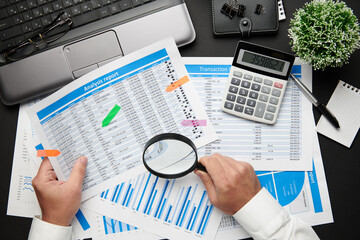 Top view of businessman's hands working with financial reports. Modern black office desk with...
