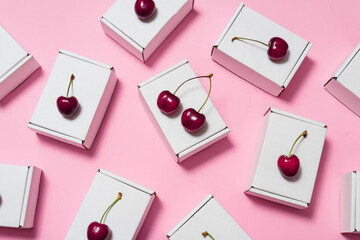 Set of cardboard boxes on pink background, decorated with fresh cherry