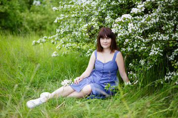 beautiful woman sitting under blooming tree in summer garden