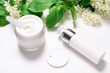 Obraz na płótnie Canvas Face cream in jar on white table with bird cherry