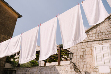 Fototapeta na wymiar White towels are dried between houses in Perast, Montenegro.