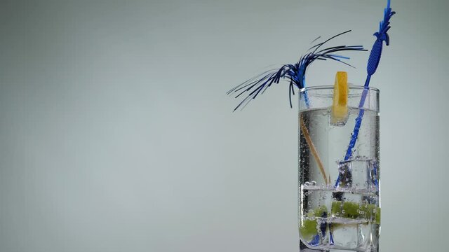Cooling summer drink with lemon and kiwi rotate on a white background. Transparent fizzy lemonade. Fresh citrus cocktail, healthy drink concept.