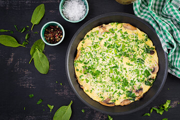 Spinach and mushroom omelette. Frittata made of eggs, mushrooms and spinach. Italian cuisine. Top view, flat lay, copy space