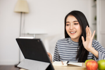 Online  Video Call Conference of Work Team from Home Office.Smiling young asian woman sit at home speaking.online with internet teacher learn language talk .young woman say hello.