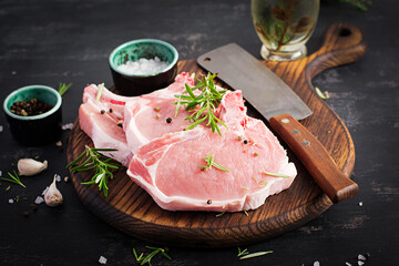 Raw pork steaks оn the dark table.