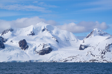 Fototapeta na wymiar Snow covered mountain with glaciers ending in the ocean on an island called 