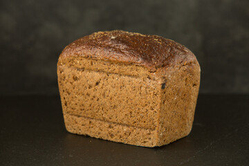 Brown rye bread on a dark stone background.Concept Healthy Lifestyle
