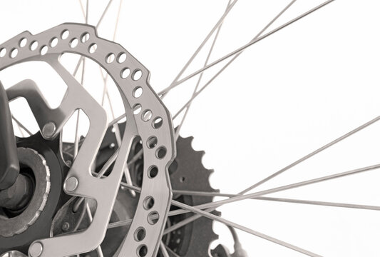 Close-up of  a mountain bike wheel with brake disc, gear and spokes in black and white isolated on white background