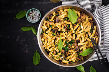Fusilli pasta with spinach and mushrooms on a pan. Vegetarian / vegan  food. Italian cuisine. Top view, flat lay, copy space