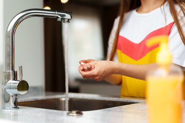 Close up of a woman washing her hands in a kitchen sink