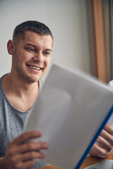 Young Caucasian guy holding file with papers