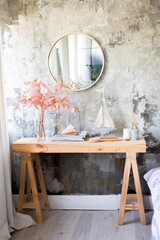 A modern wooden table, a round mirror, flowers and accessories for the house with a copy on the...