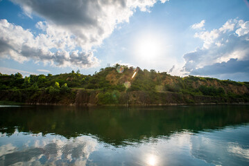 Fototapeta na wymiar Stone quarry with lake. Stone mining in the canyon. quarry background of trees and sun.