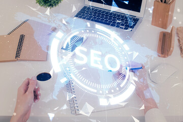 Multi exposure of woman's hands making notes with SEO icon. Concept of Search engine optimization