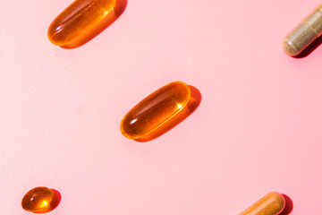 One omega 3 pill on pink background. Flat lay with harsh light and shadow. Minimal style