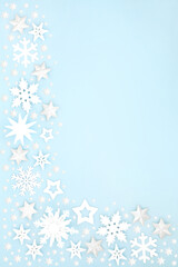 Fototapeta na wymiar Christmas snow covered border with white star, snowflake & ball bauble decorations on pastel blue background. Xmas & winter & New Year composition for the festive holiday season. 