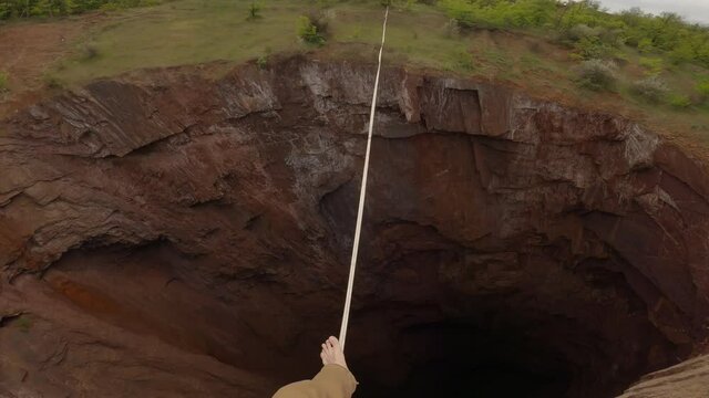POV of the slackliner walking on the tightrope over a huge scary quarry, 4k