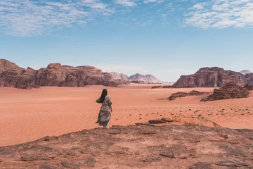 Gordijnen Young Asian traveller with local Arab dress standing on top of mountain and enjoying landscape of Wadi Rum desert, Jordan, Arab © skazzjy