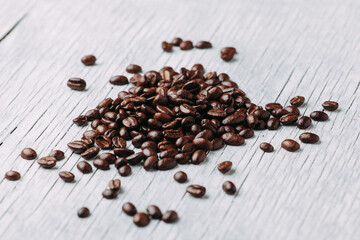 A scattering of coffee beans on a white wooden background..