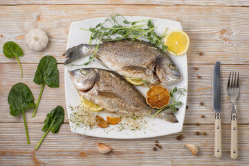 Plate with fried dorado and ingredients on a wooden background.Top view flat layout.
