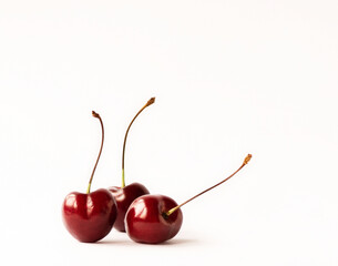 Three ripe cherries on a light background with space for text.