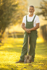 Senior gardener gardening in his permaculture garden - holding a spade