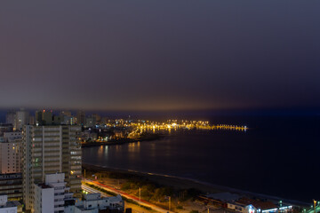 Long exposure panoramic coast view of the illuminated harbor, the calm dark water, the car lights...