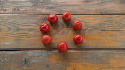 Naklejka na ściany i meble Ring of tomato moving in the middle of wooden table. Group of fresh raw vegetables. 