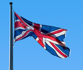 British flag (Union Jack) fluttering in the breeze against a clear blue sky