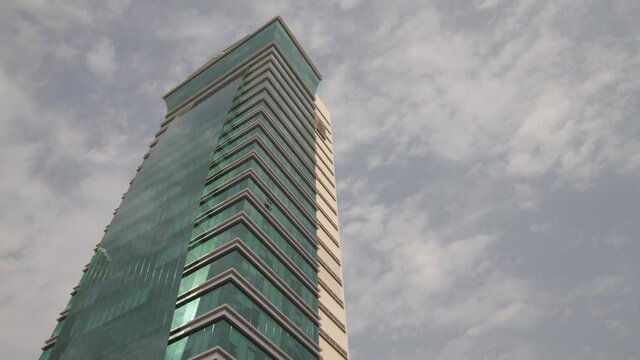 Timelapse of a modern lone skyscraper against a white cloudy sky in Bahrain