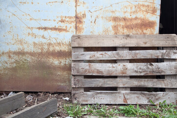 Fototapeta na wymiar Wooden box near a rusty metal wall
