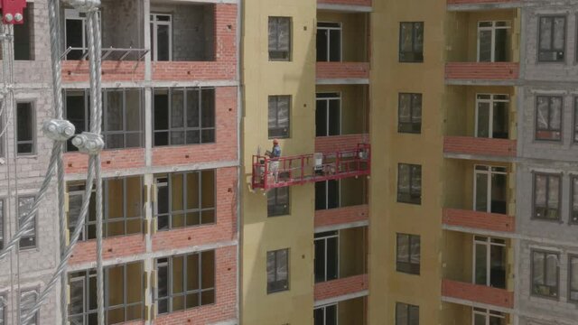 Workers in the construction cradle make cladding