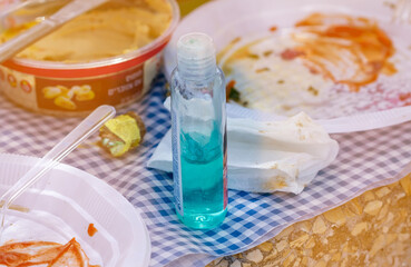 A bottle of gel for hand disinfection stands on a picnic table. Picnic in the nature.