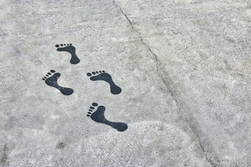 foot prints on a concrete floor leading to the beach direction as a directional sign