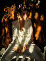 a beautiful girl in a white pantsuit with ginger is sitting in a brown leather chair - 357162814