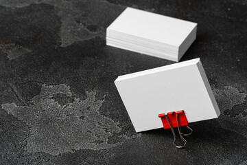 White businesscards united with a paper clip on a black rough background
