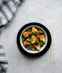 Cauliflower salad with bell pepper, onion and garlic in Asian sauce. Gray background, top view, vertical orientation.