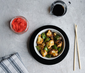 Warm cauliflower salad with wok vegetables in Asian sauce. Background gray, top view horizontal orientation.