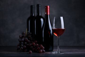 The red wine in the glass, along with a bottle of wine made from red grapes, is laid on a wooden floor and a beautiful backdrop. Ready for partying