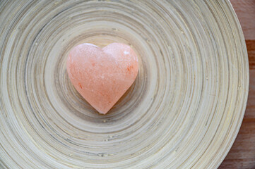 Fototapeta na wymiar Pink stone heart with rock stones in background. Symbol of love.