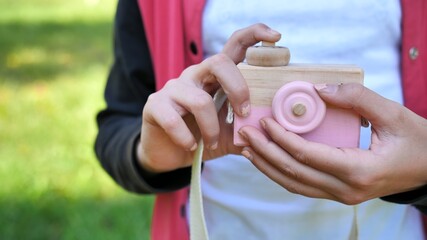 Toy wooden camera in the hands of a teenage girl.