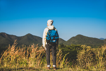  blurry Soft focus, Asian young man in a long shirt and black hat hiking at mountain peak above clouds Hiker outdoors. In the morning.