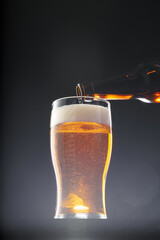 Beer pouring into glass on black background