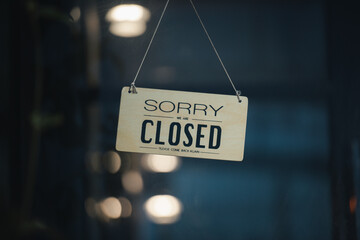 sorry we are closed sign hanging outside a restaurant, store, office or other. Closed sign in a shop showroom with reflections bokeh.