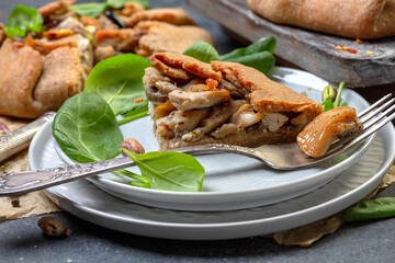 Piece of rye pie with chicken, onions and mushrooms close-up.