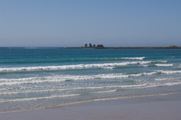 Gentle waves on East Beach with Griffiths Island lighthouse in the background, Port Fairy, Victoria, Australia.