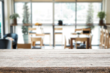 Empty wooden desk space platform over blurred restaurant or coffee shop background for product display montage.