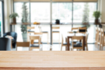 Empty wooden desk space platform over blurred restaurant or coffee shop background for product display montage.