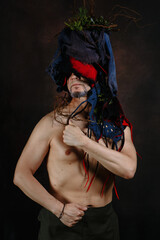Art project with a man whose headdress is made of fabric, moss and branches